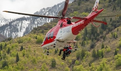 (Chris Samuels | The Salt Lake Tribune) An Intermountain LifeFlight helicopter hoists a Search and Rescue volunteer and the survivor of the Big Willow Apron avalanche before landing near Hidden Valley Park in Sandy, Thursday, May 9, 2024.